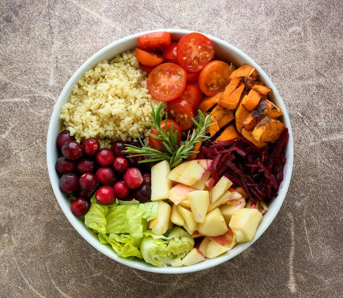 Bunte Bowl mit Gemüse, Obst und Couscous als Sinnbild für gesunde Ernährung